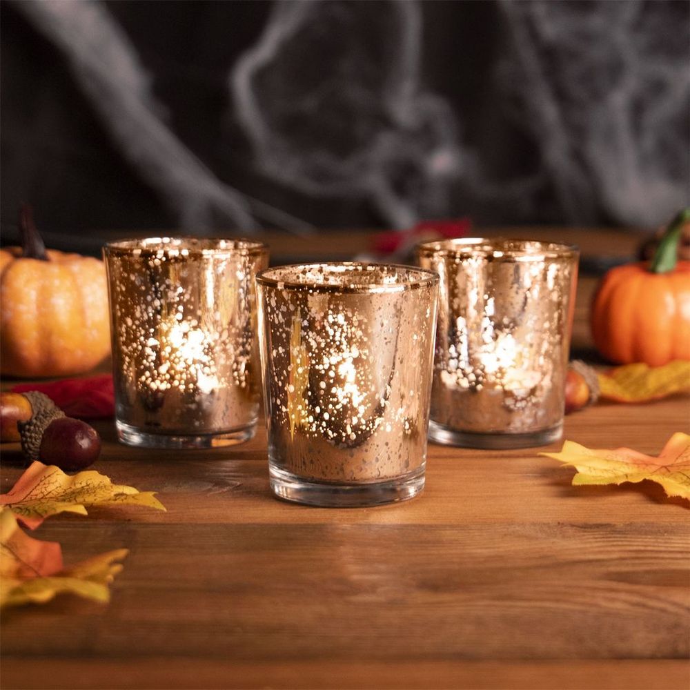 Speckled gold tealight holders burning tealights on table